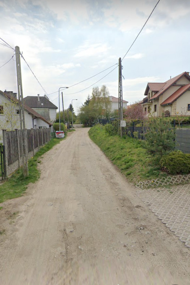 Zdjęcie przedstawia ulicę pływacką polna droga po lewej i prawej stronie domy Zdjęcie przedstawia ulicę pływacką polna droga po lewej i prawej stronie domy